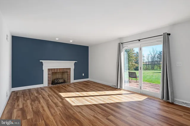 a view of empty room with wooden floor and fireplace