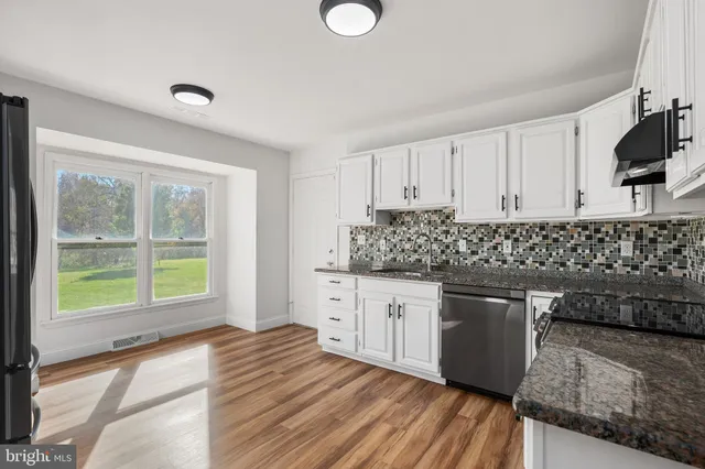 a kitchen with granite countertop a sink and a stove top oven