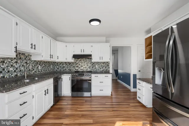 a kitchen with granite countertop a refrigerator oven a sink and dishwasher