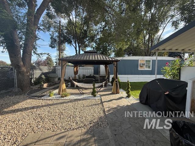 111 East Simplot Boulevard Caldwell, ID 83605 - Photo 3 of 17 Private outdoor space featuring a covered gazebo, stone patio, gravel landscaping, and mature trees