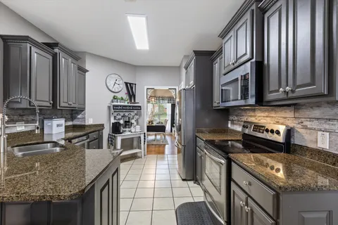 a kitchen with stainless steel appliances granite countertop a stove top oven a sink dishwasher and cabinets with wooden floor