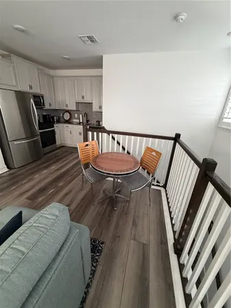a living room with couches and a dining table with wooden floor