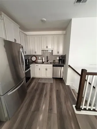 a kitchen with granite countertop a refrigerator stove and wooden floor