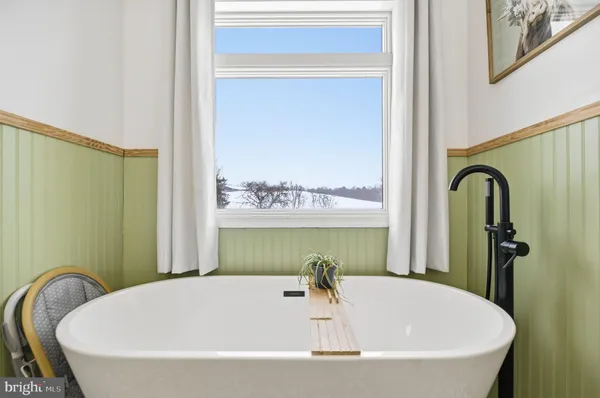 a white bath tub sitting in a bathroom next to a window