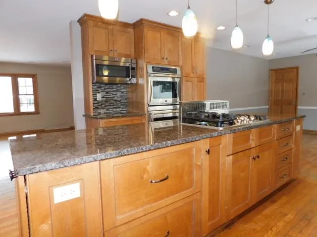 a view of an empty room with wooden floor and a ceiling fan