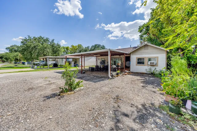 a view of a house with a yard and large trees