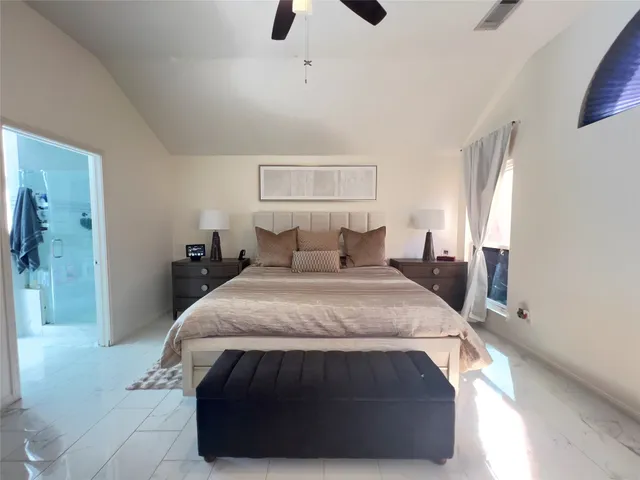 a spacious bedroom with a bed and a flat screen tv