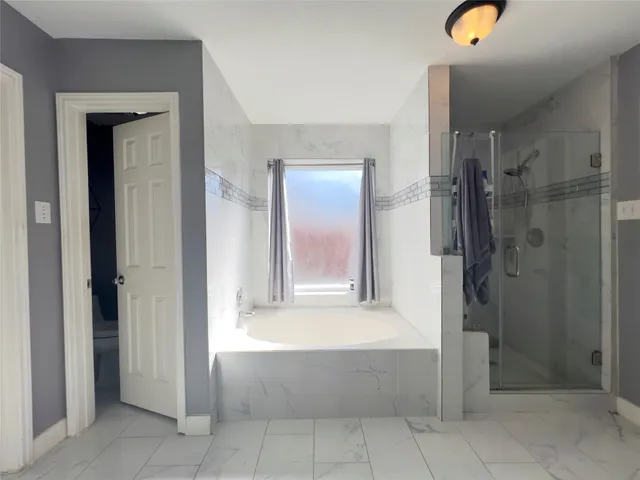 a large white bathroom with a bathtub sink and mirror