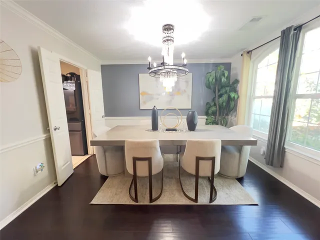 a dining room with wooden floor a chandelier a wooden table and chairs