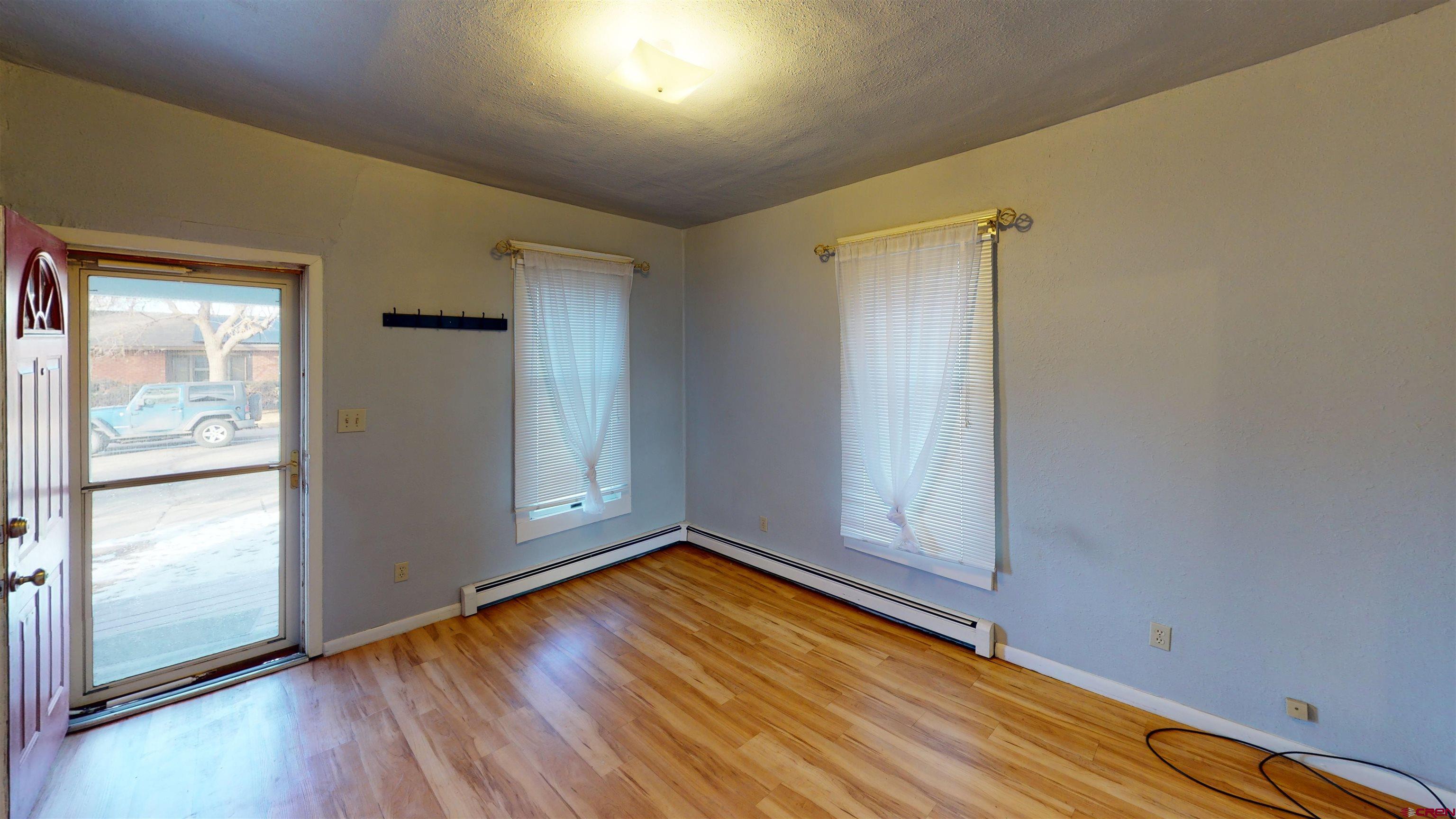 1016 Lincoln Avenue Alamosa, CO 81101 - Photo 3 of 10 an empty room with wooden floor door and windows