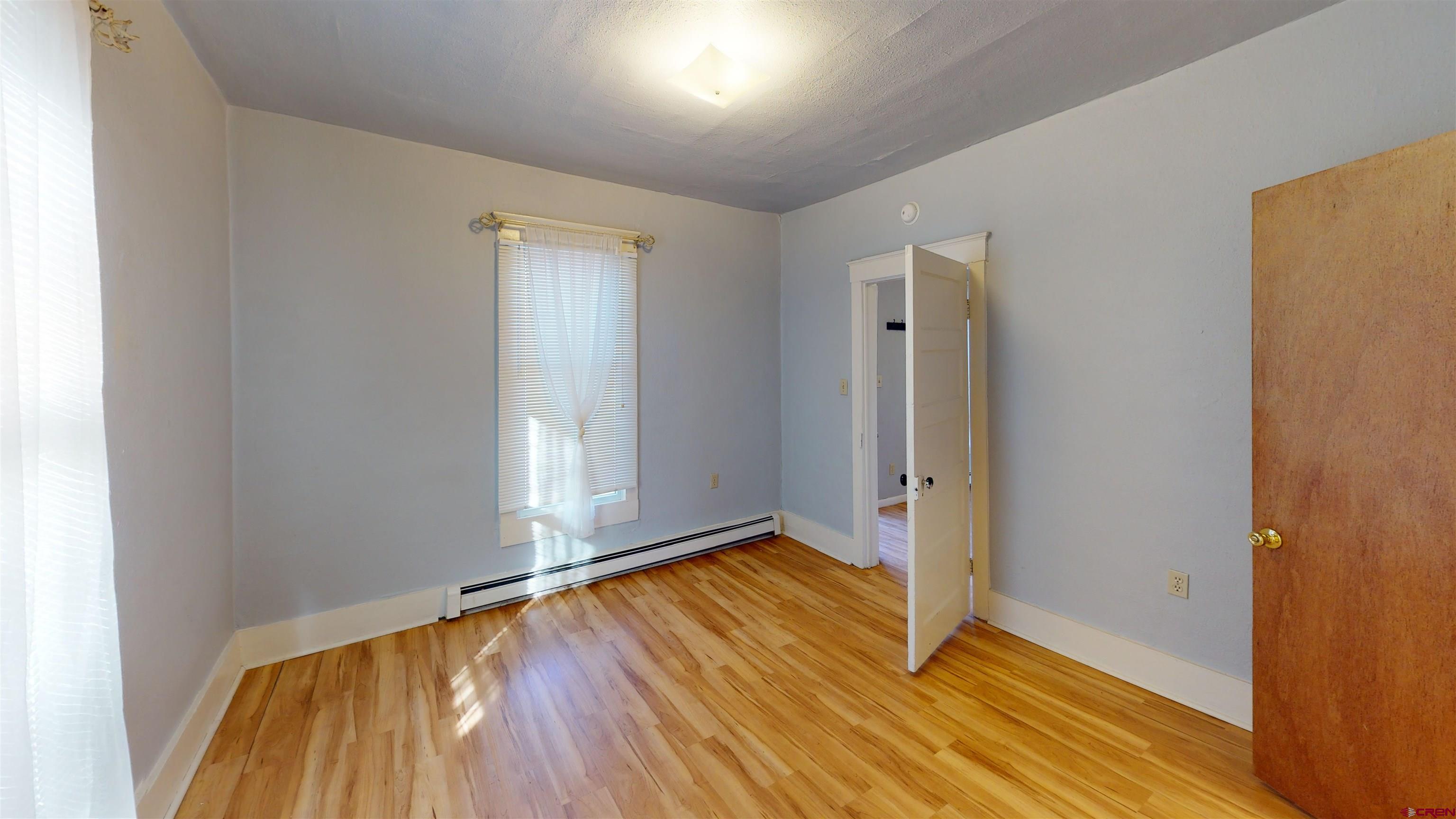 1016 Lincoln Avenue Alamosa, CO 81101 - Photo 6 of 10 an empty room with wooden floor and a window