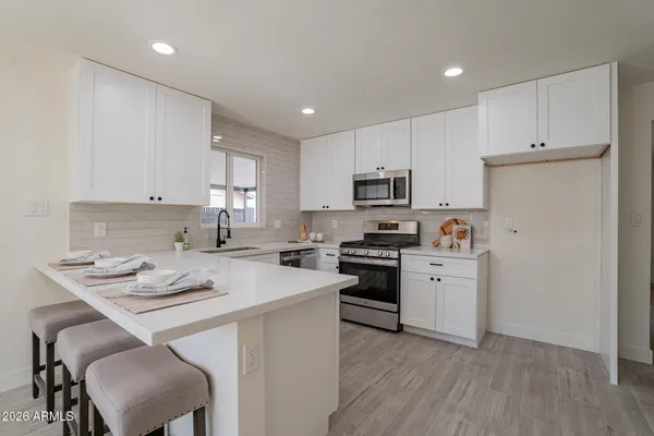 a kitchen with a sink a stove a refrigerator and white cabinets