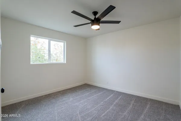an empty room with a window and a ceiling fan