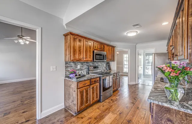 a kitchen with stainless steel appliances granite countertop a stove a sink dishwasher and a refrigerator with wooden floor