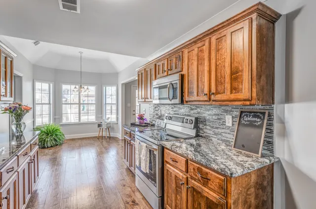 a kitchen with stainless steel appliances granite countertop a stove a sink dishwasher and a wooden cabinets