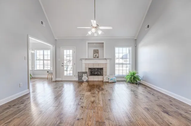 a view of an empty room with window and wooden floor