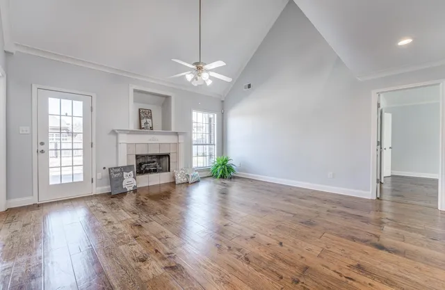 an empty room with wooden floor fireplace chandelier and windows