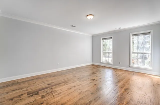 an empty room with wooden floor and windows