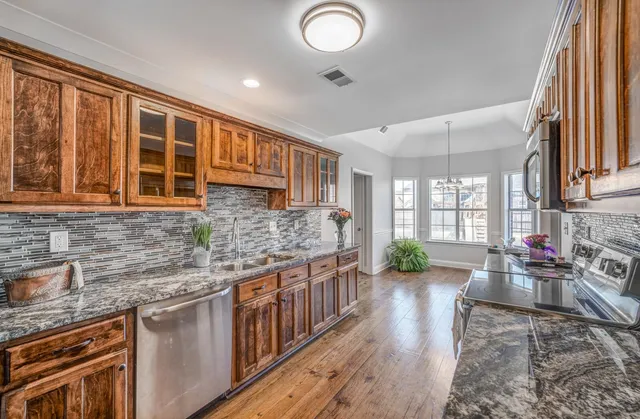 a kitchen with stainless steel appliances granite countertop a stove a sink and a granite counter tops with wooden floors