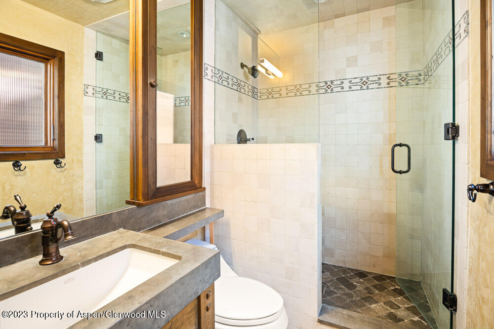 114 East Bleeker Street, Unit 102 Aspen, CO 81611 - Photo 11 of 21 a bathroom with a granite countertop sink a mirror and a shower