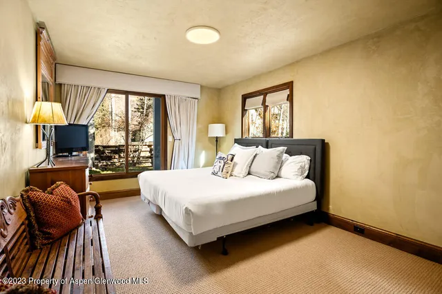 a spacious bedroom with a bed and glass windows