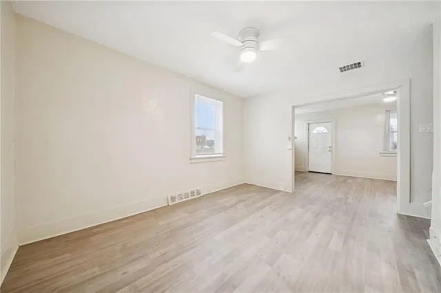 an empty room with wooden floor and windows