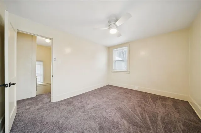 an empty room with a ceiling fan and a window