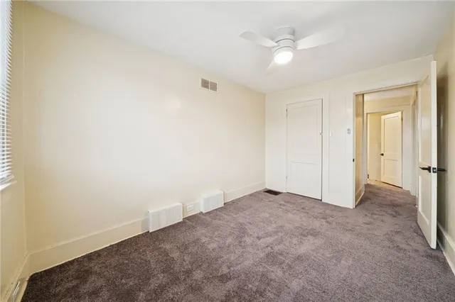 an empty room with a ceiling fan and a window