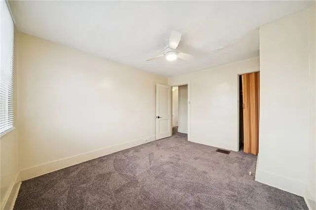 an empty room with a ceiling fan and a window