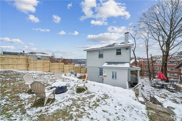 a backyard of a house with large tree and wooden fence