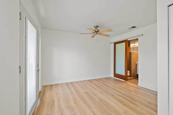 a view of an empty room with window and wooden floor