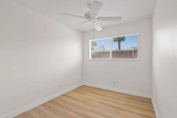 an empty room with a window and a fan
