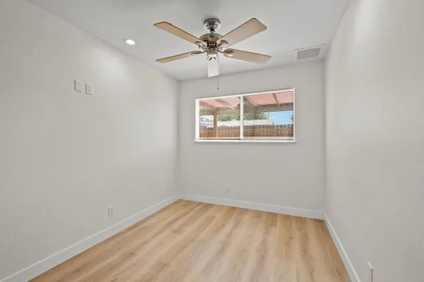 an empty room with a window and a fan