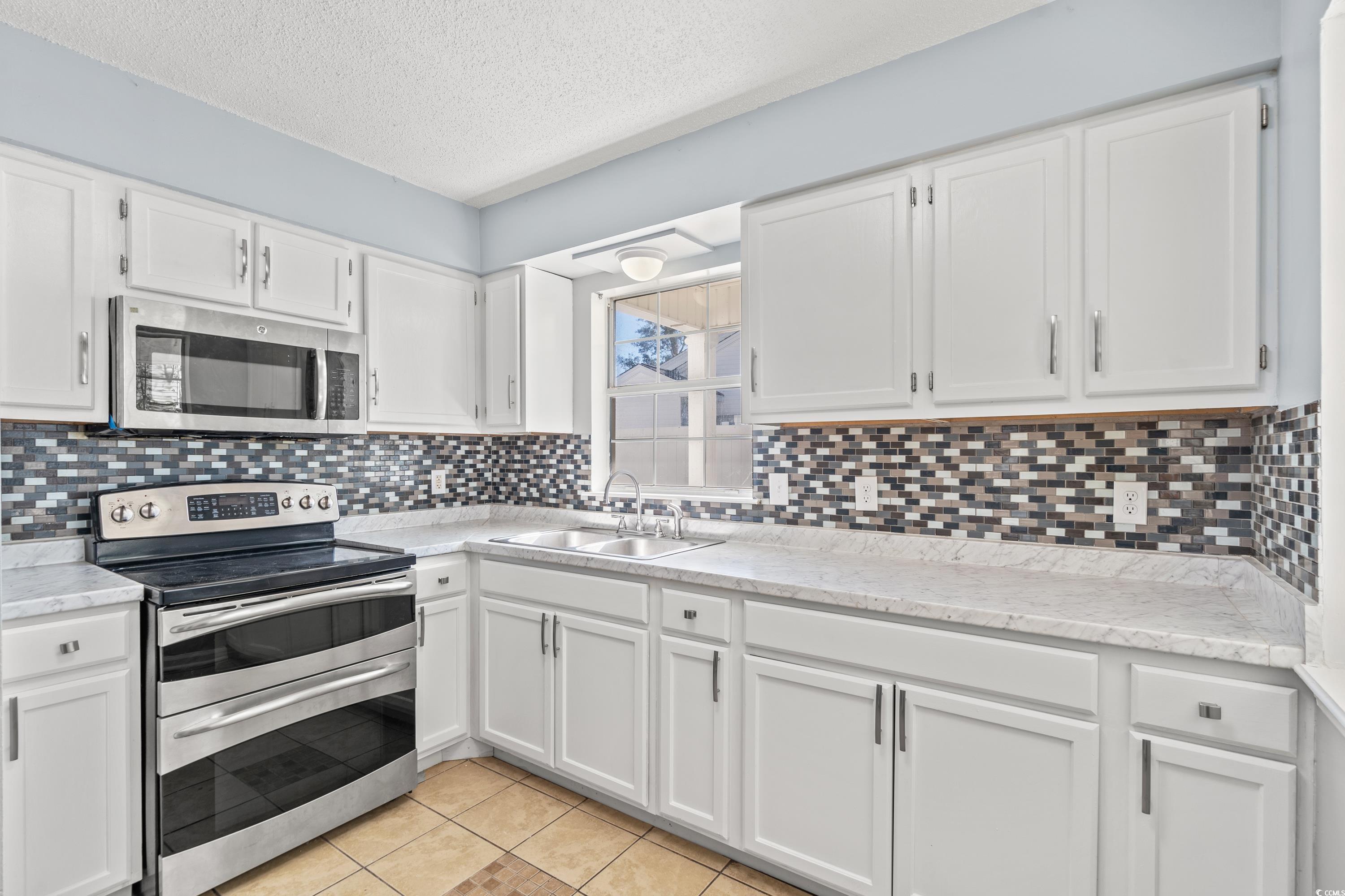 1024 Futrell Drive, Unit 1024 Myrtle Beach, SC 29577 - Photo 14 of 20 Kitchen featuring white cabinetry, sink, appliance