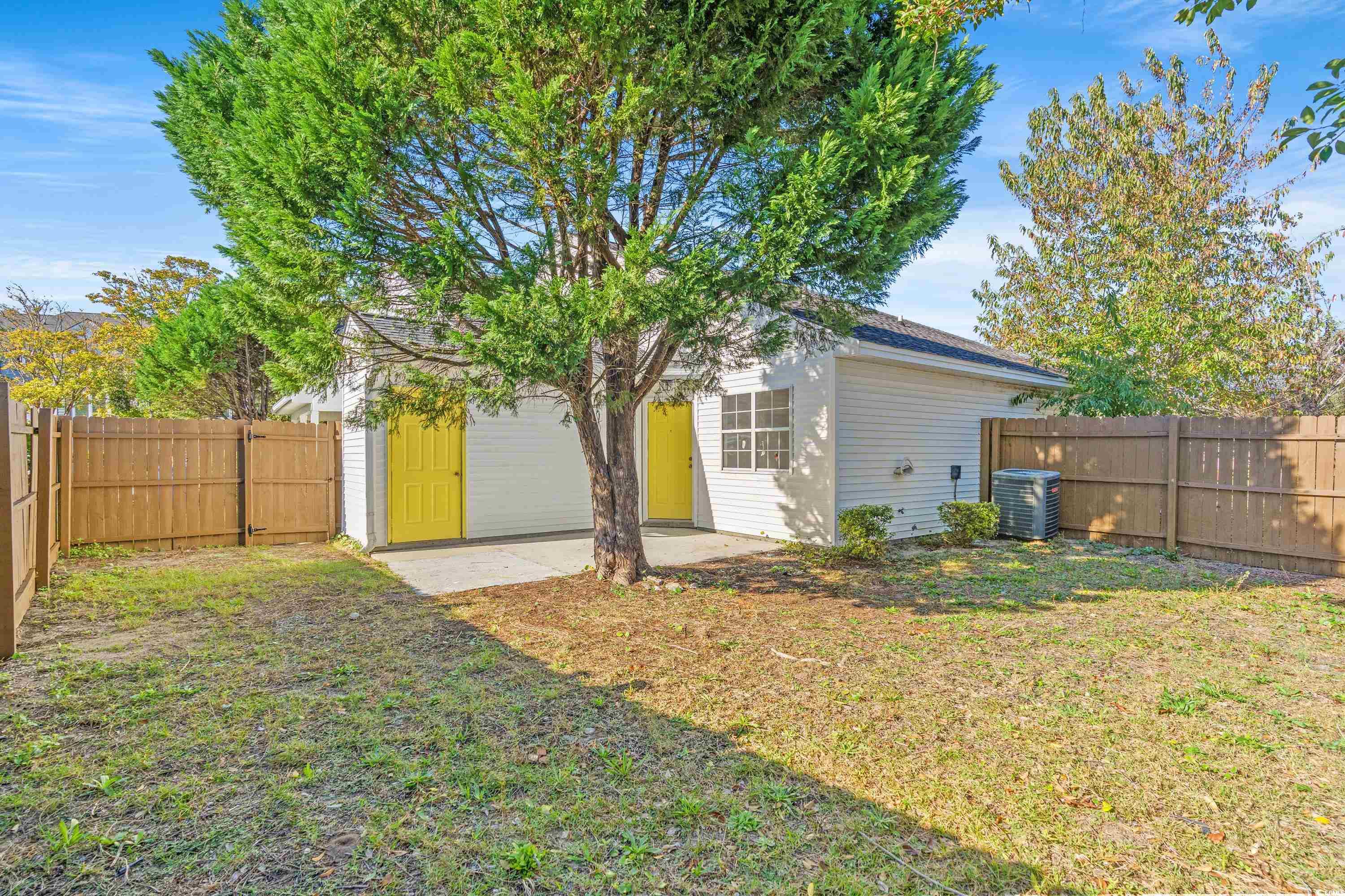 Back of house with central AC unit, a lawn, and a
