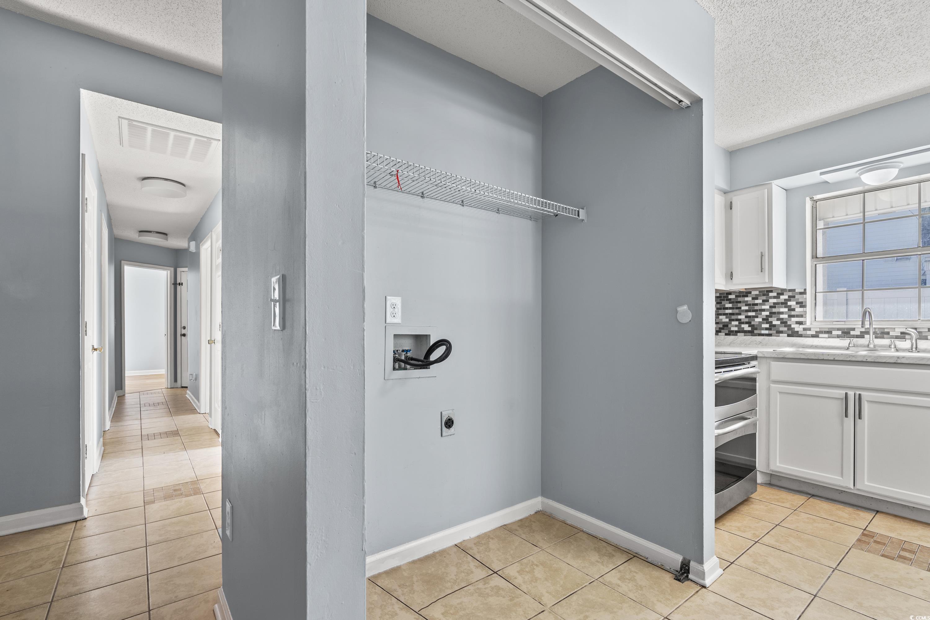 Laundry room with sink, washer hookup, light tile