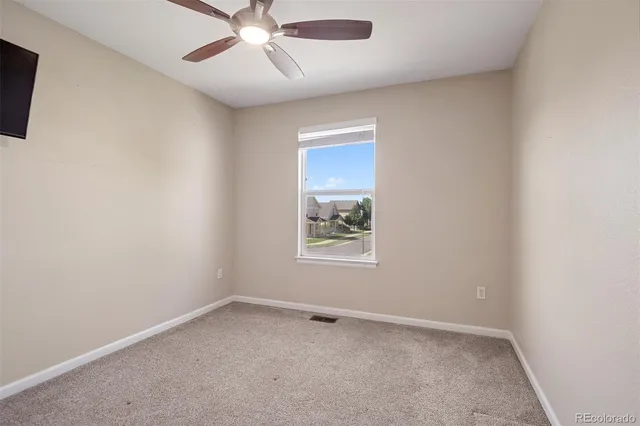 an empty room with a window and a fan