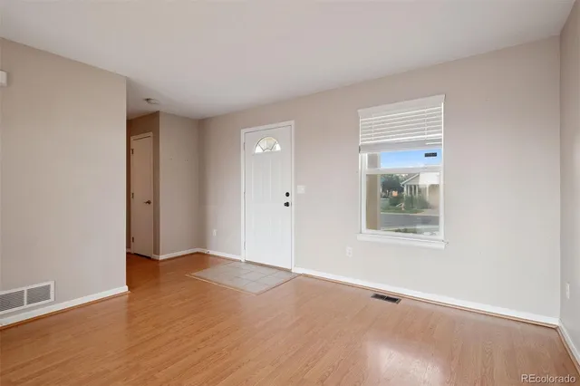 an empty room with wooden floor and windows