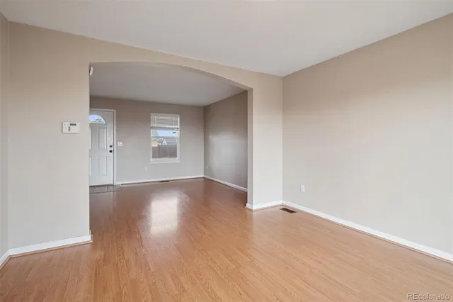 an empty room with wooden floor and windows