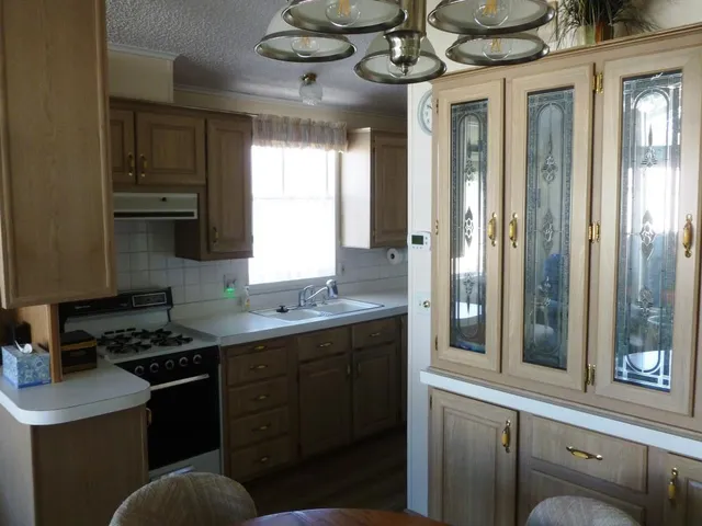 a kitchen with stainless steel appliances granite countertop a sink a stove and a wooden cabinets