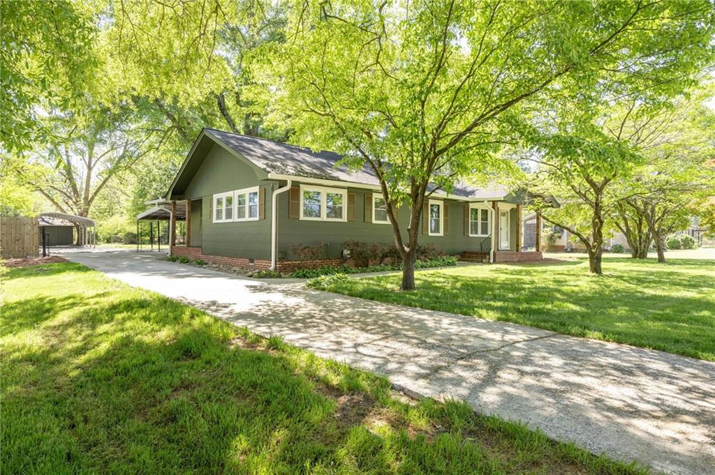 a front view of a house with a garden and trees