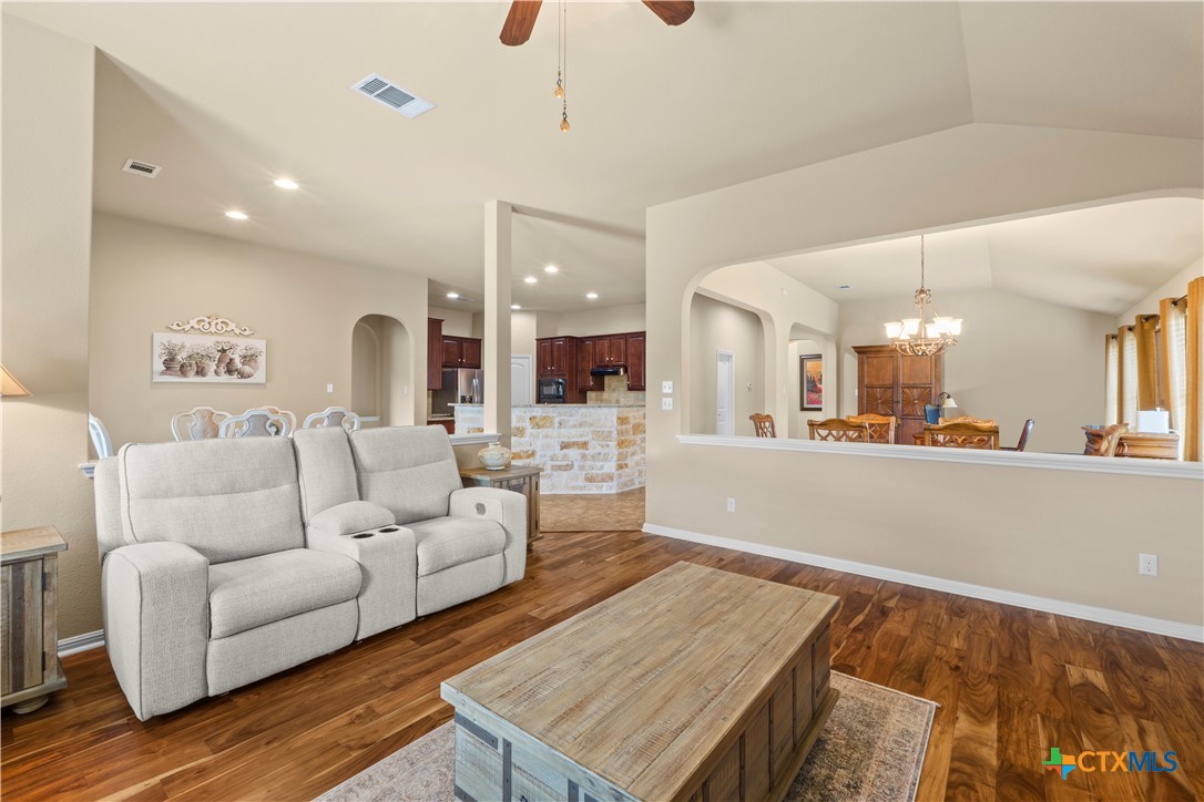 20525 Jackies Ranch Boulevard Pflugerville, TX 78660 - Photo 6 of 30 Living room with arched walkways, a ceiling fan, dark Acacia wood engineered flooring, lofted ceiling, and hanging lights