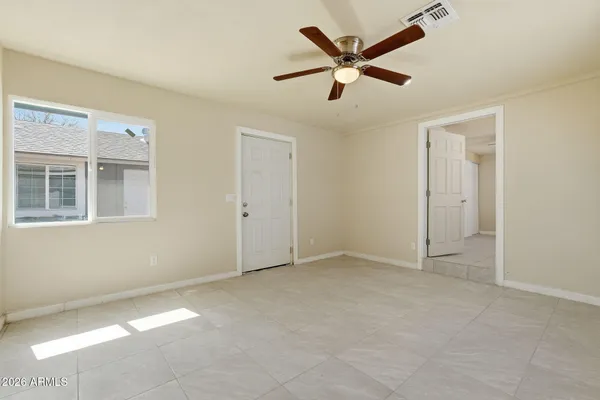 an empty room with windows and fan