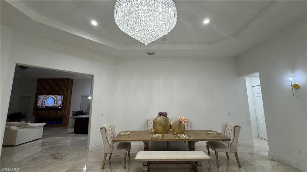 5340 Allen Place Ave Maria, FL 34142 - Photo 11 of 35 Dining area featuring a raised ceiling, light marble finish flooring, a chandelier, and recessed lighting