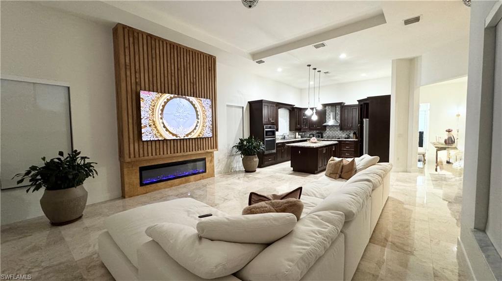 5340 Allen Place Ave Maria, FL 34142 - Photo 12 of 35 Living area featuring a glass covered fireplace, recessed lighting, and light marble finish flooring