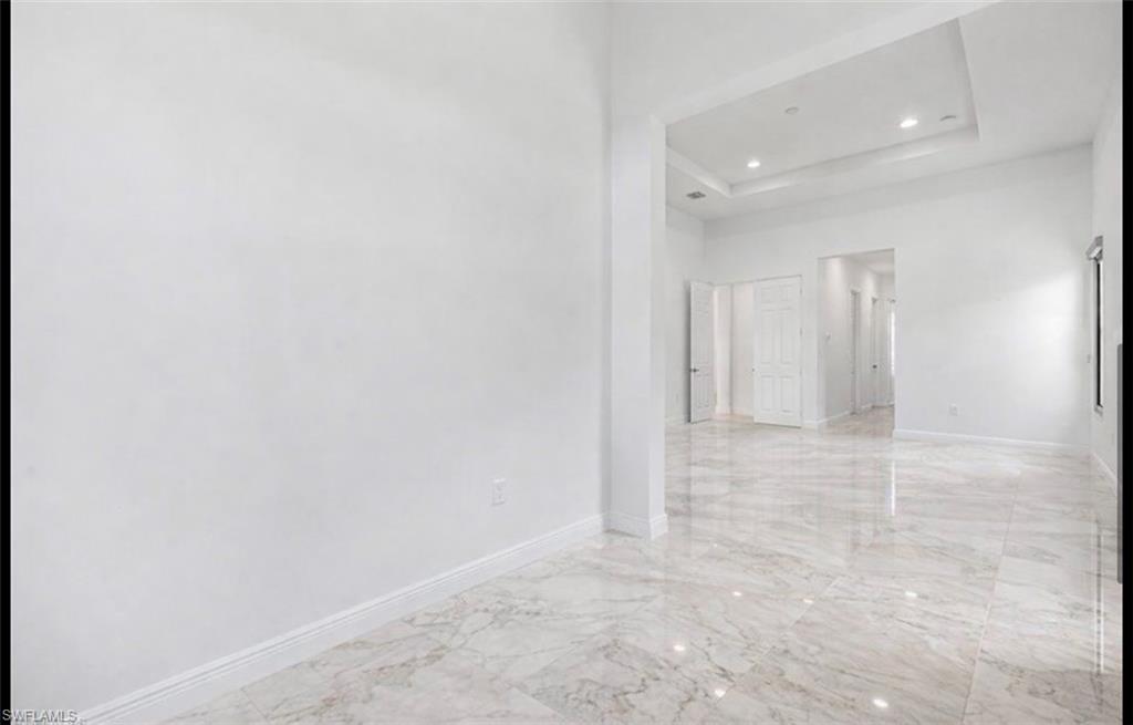 5340 Allen Place Ave Maria, FL 34142 - Photo 14 of 35 Empty room featuring a tray ceiling, light marble finish flooring, recessed lighting, and a towering ceiling