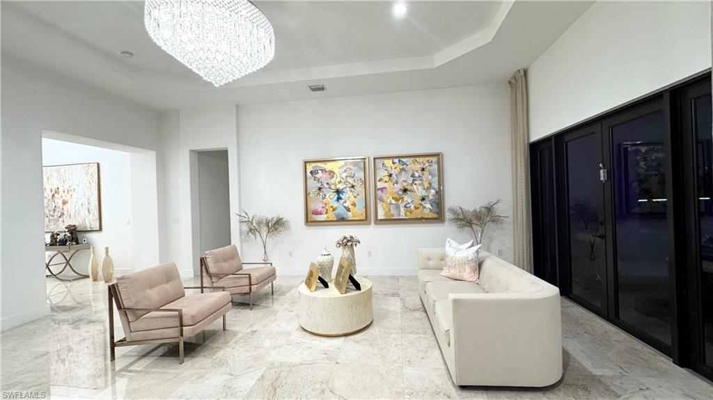 5340 Allen Place Ave Maria, FL 34142 - Photo 10 of 35 Living area featuring a tray ceiling, a chandelier, and marble tiled floors