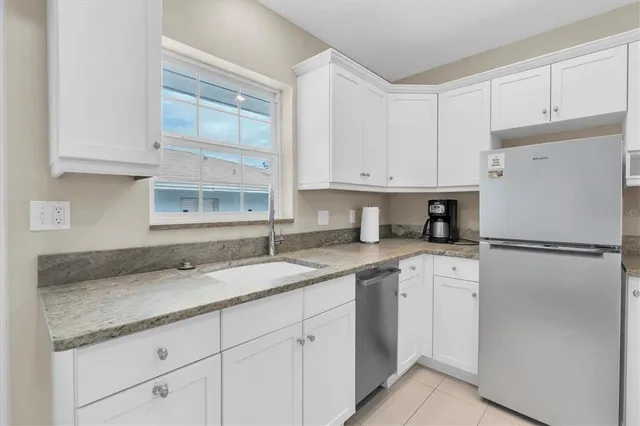 a kitchen with a sink dishwasher a refrigerator and white cabinets
