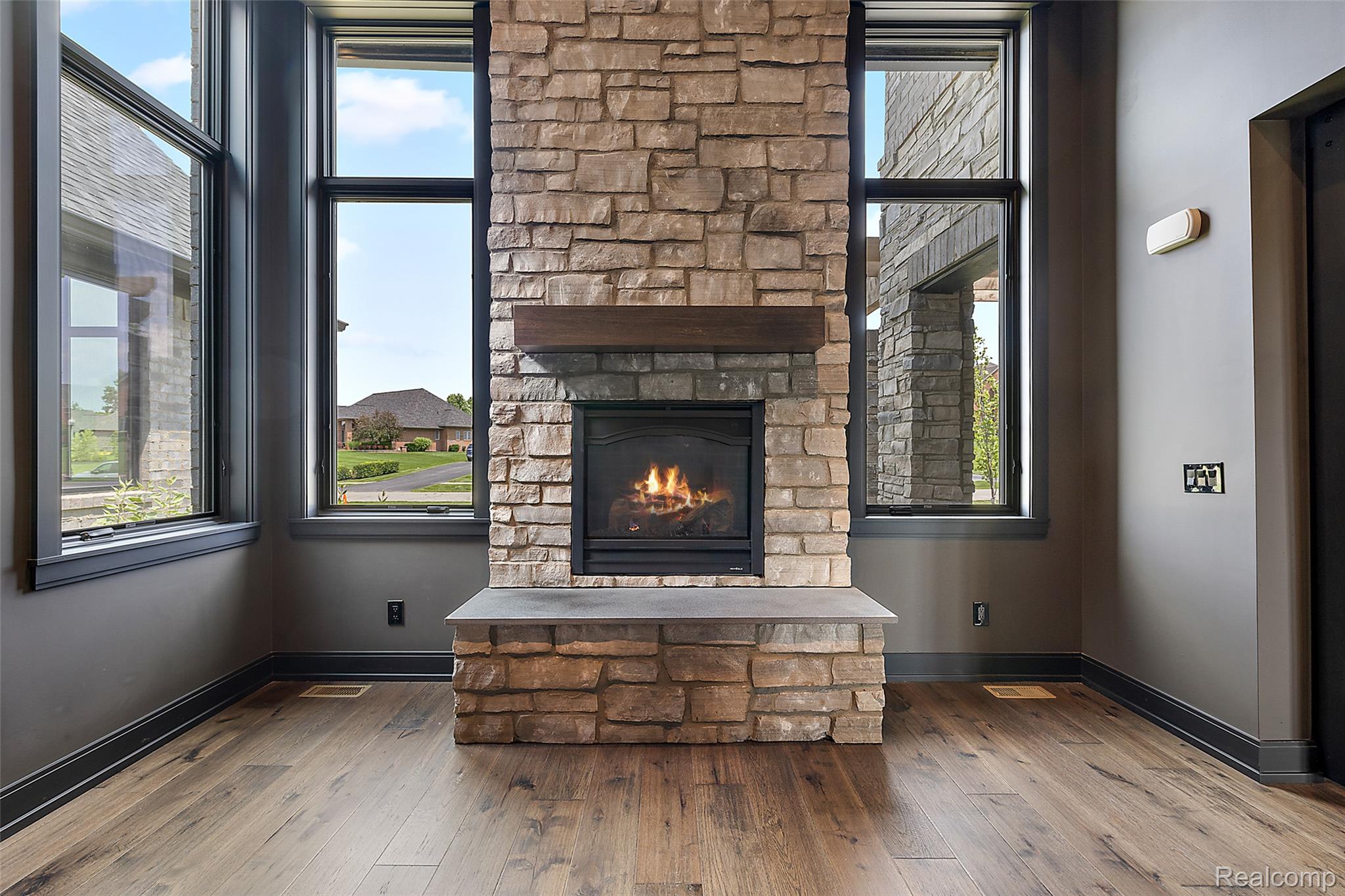 Unfurnished living room with hardwood / wood-style flooring, a stone fireplace, and elevator