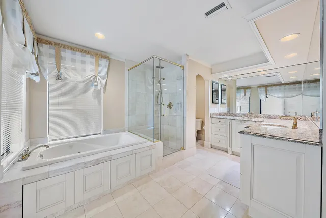 a bathroom with a granite countertop sink a mirror a shower and a bathtub